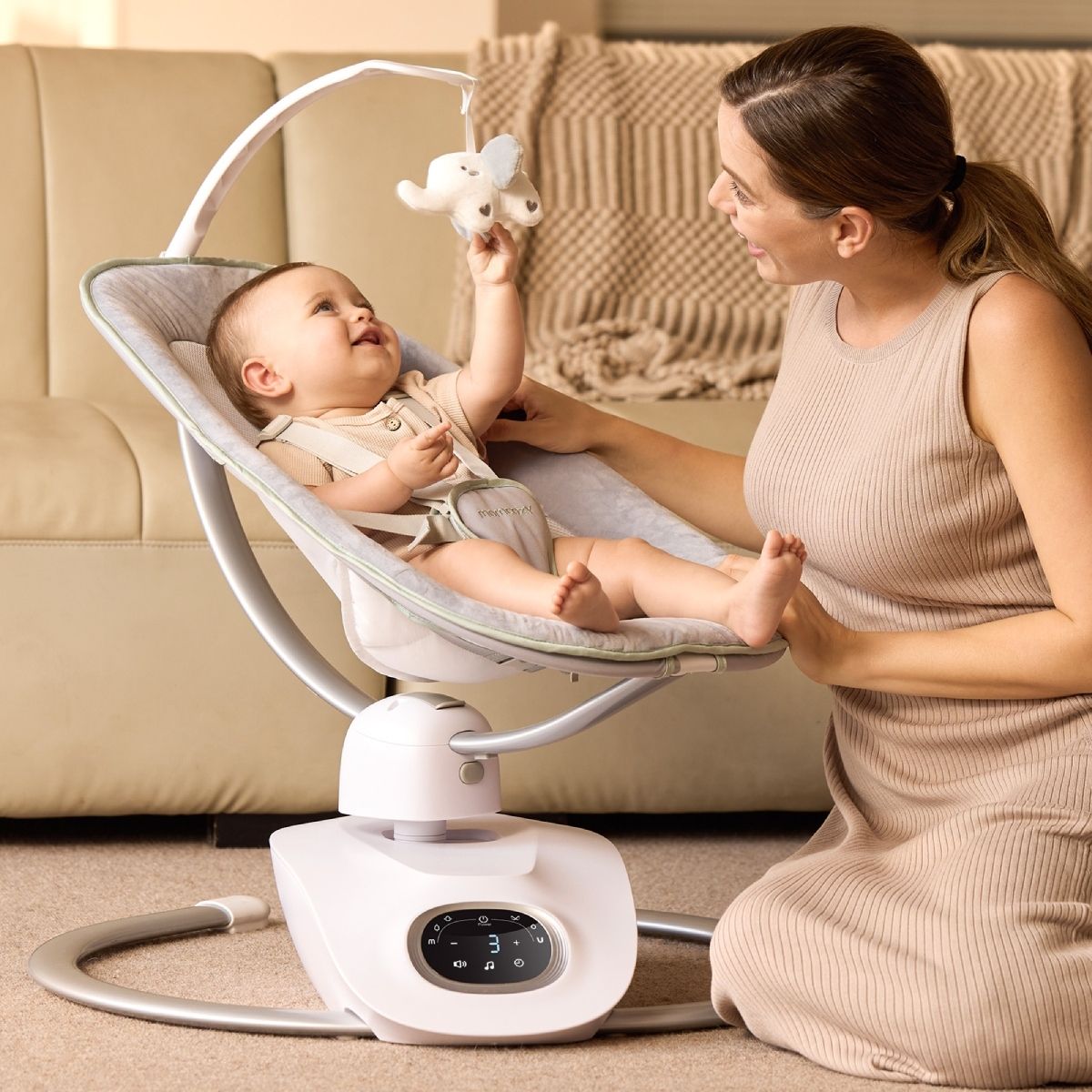 Mère et bébé interagissent avec balancelle. Bébé attrape jouet.