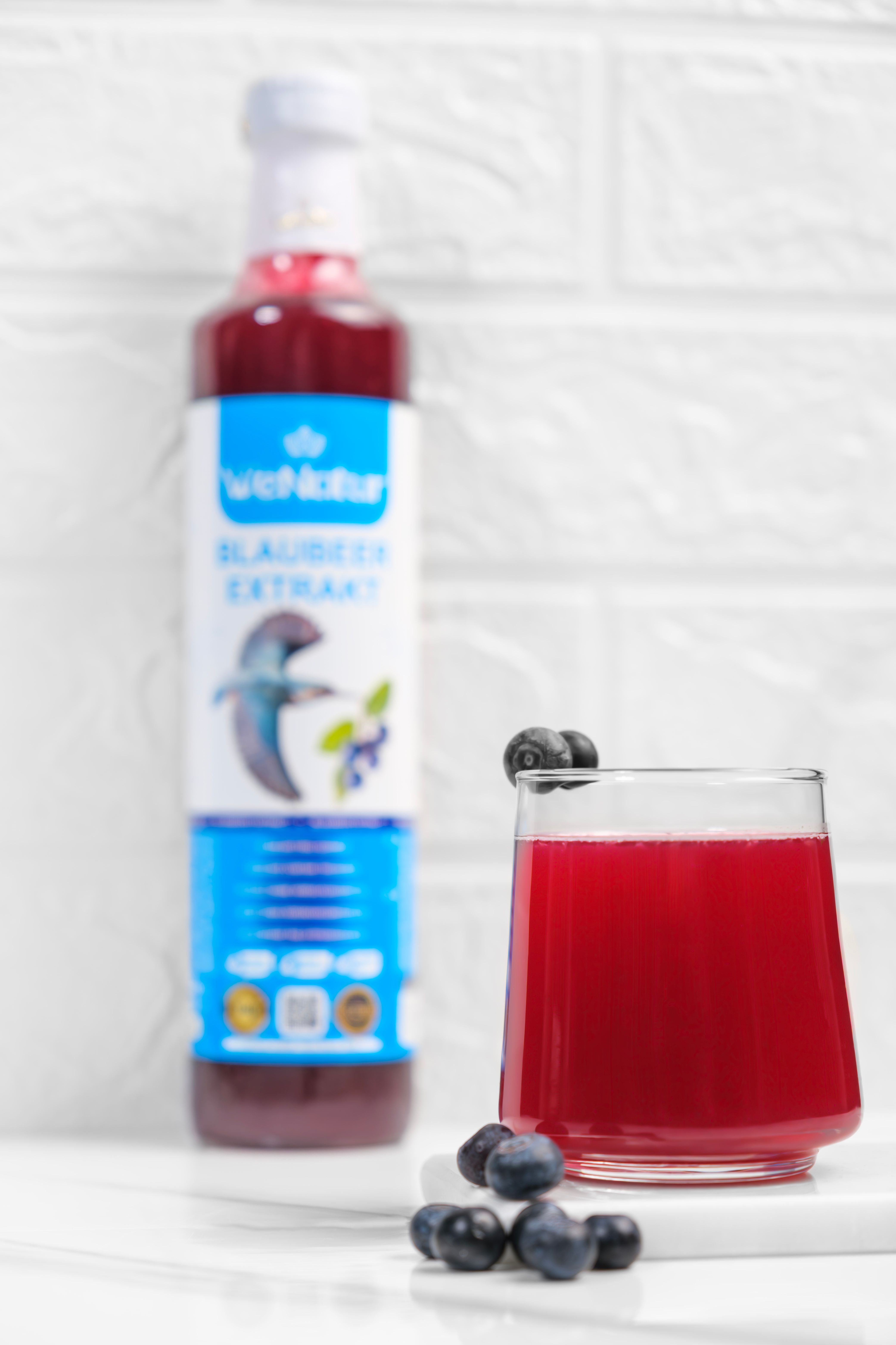 Fles WeNatur Blauwe Bes Extract met glas en bessen.