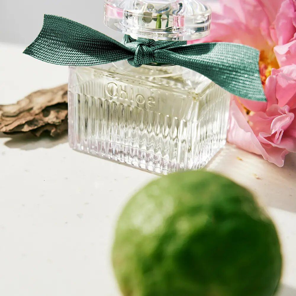 Glazen flacon met strik. Opschrift: Chloé. Flacon met groen lint. Met citroen en bloem.
