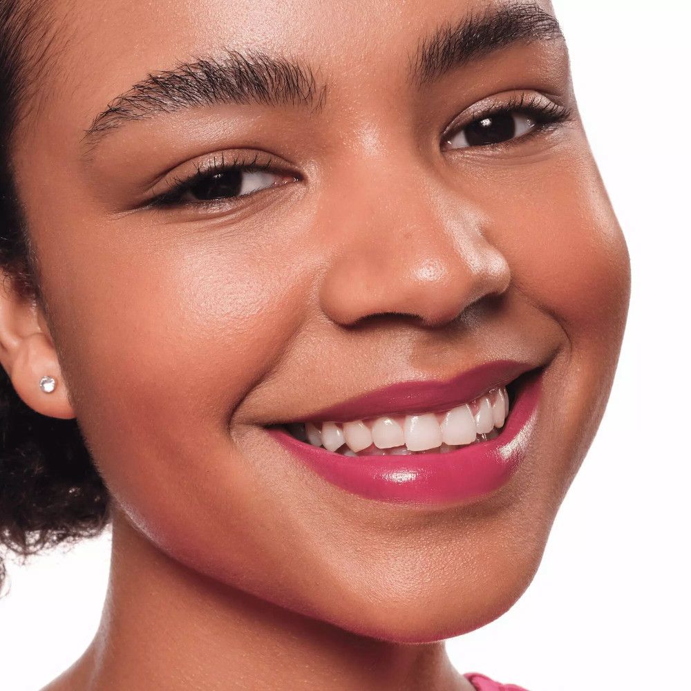 Portrait d'une femme avec un Lip Tint rose. Elle sourit. Teint foncé.