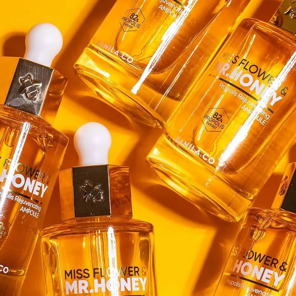 Meerdere glazen flacons met goudkleurig serum. Opschrift: Miss Flower & Mr. Honey. 82% Propolis Extract.