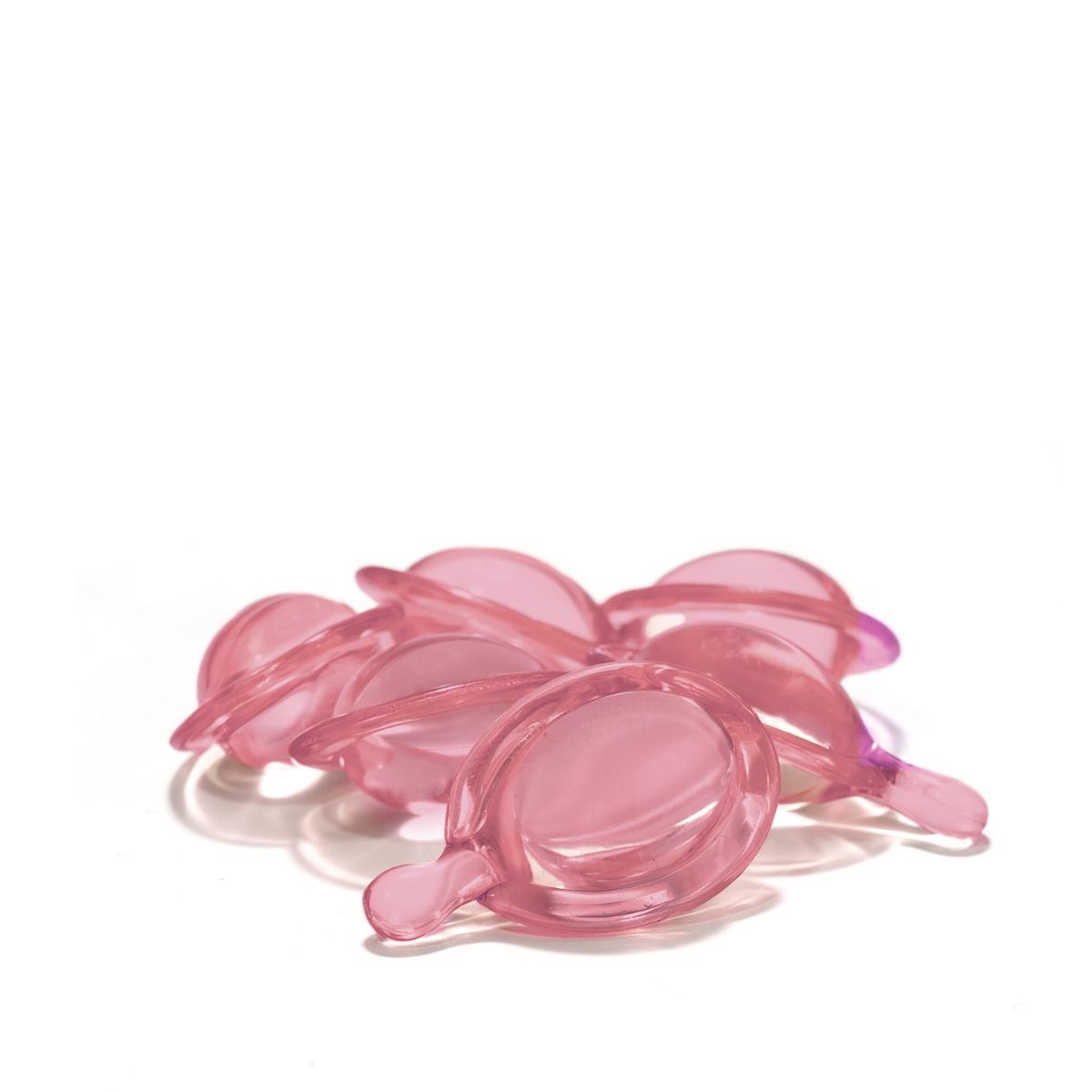 Close-up van meerdere roze, ovale haarvitaminecapsules met een kleine tuit. Op witte achtergrond.