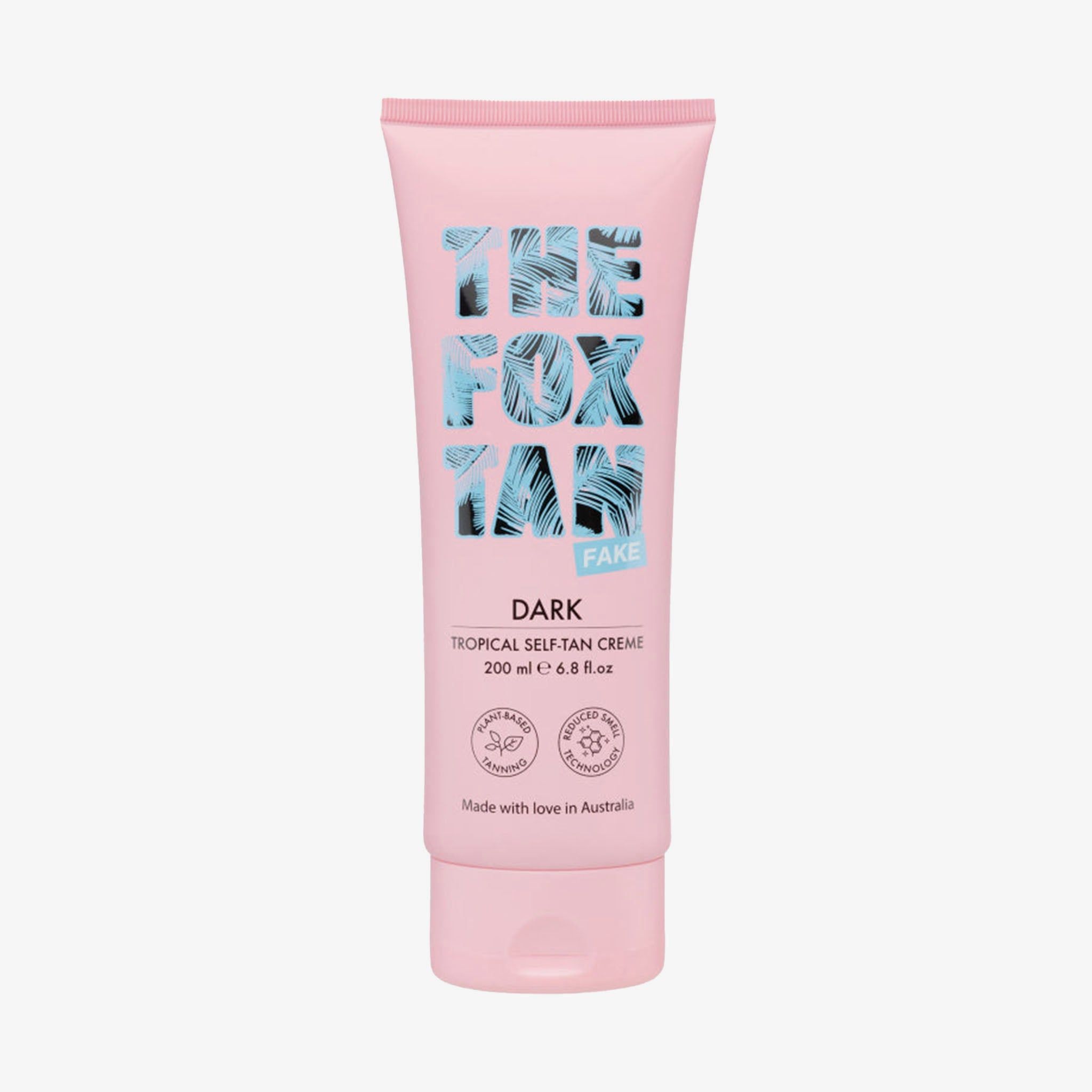 Tube rose avec logo bleu et texte. "Dark Tropical Self-Tan Creme" et certifications visibles.
