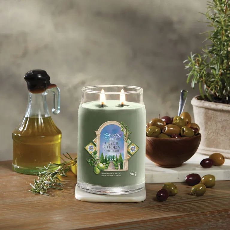 Yankee Candle Olive & Cypress kaars met twee lonten. Olijven, oliefles, rozemarijn en pot op houten oppervlak.