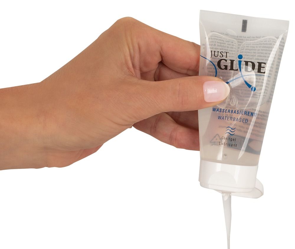Gel transparent sortant d'un tube. Inscription : JUST GLIDE, à base d'eau. Le produit est pressé hors du tube.