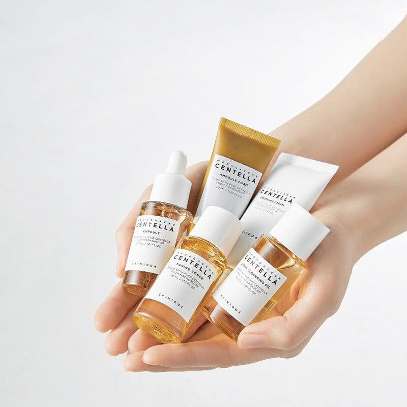 Handen die diverse huidverzorgingsproducten vasthouden. Bevat flesjes en tubes. Producten worden in de handen gehouden.