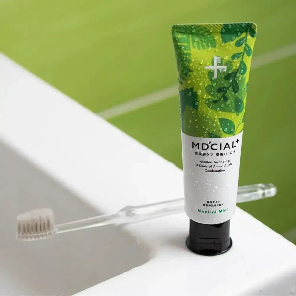 Tube de dentifrice MD'CIAL+ vert et brosse à dents. Inscription Medical Mint. Bouchon noir.