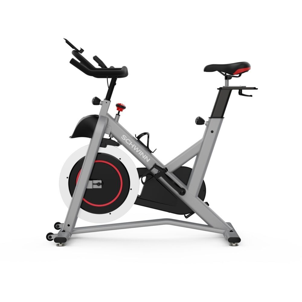 Vélo d'intérieur gris. Visible : selle, guidon, volant d'inertie. Marque : Schwinn. Accent rouge sur le volant.