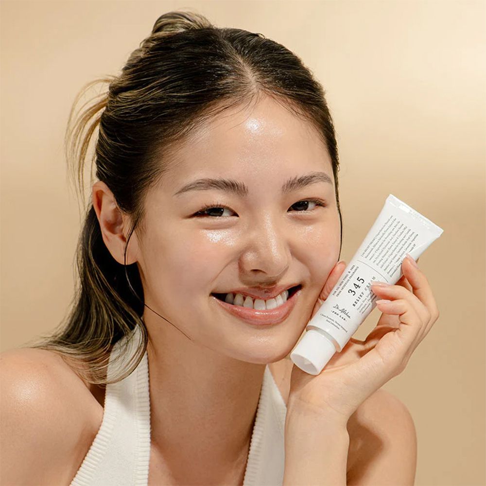 Une jeune femme tient un tube blanc de Dr. Althea 345 Relief Cream.