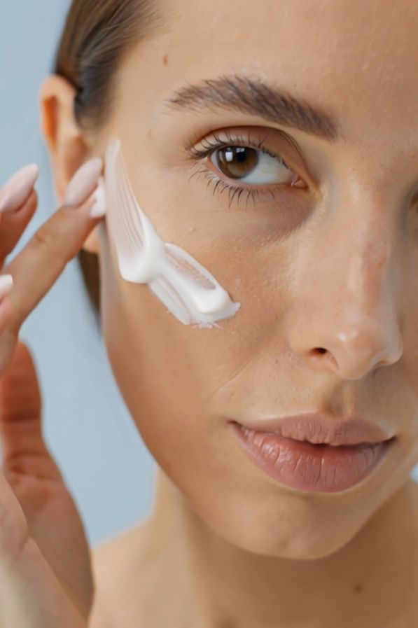 Vrouw brengt crème aan op haar gezicht. Crème zichtbaar op de huid.