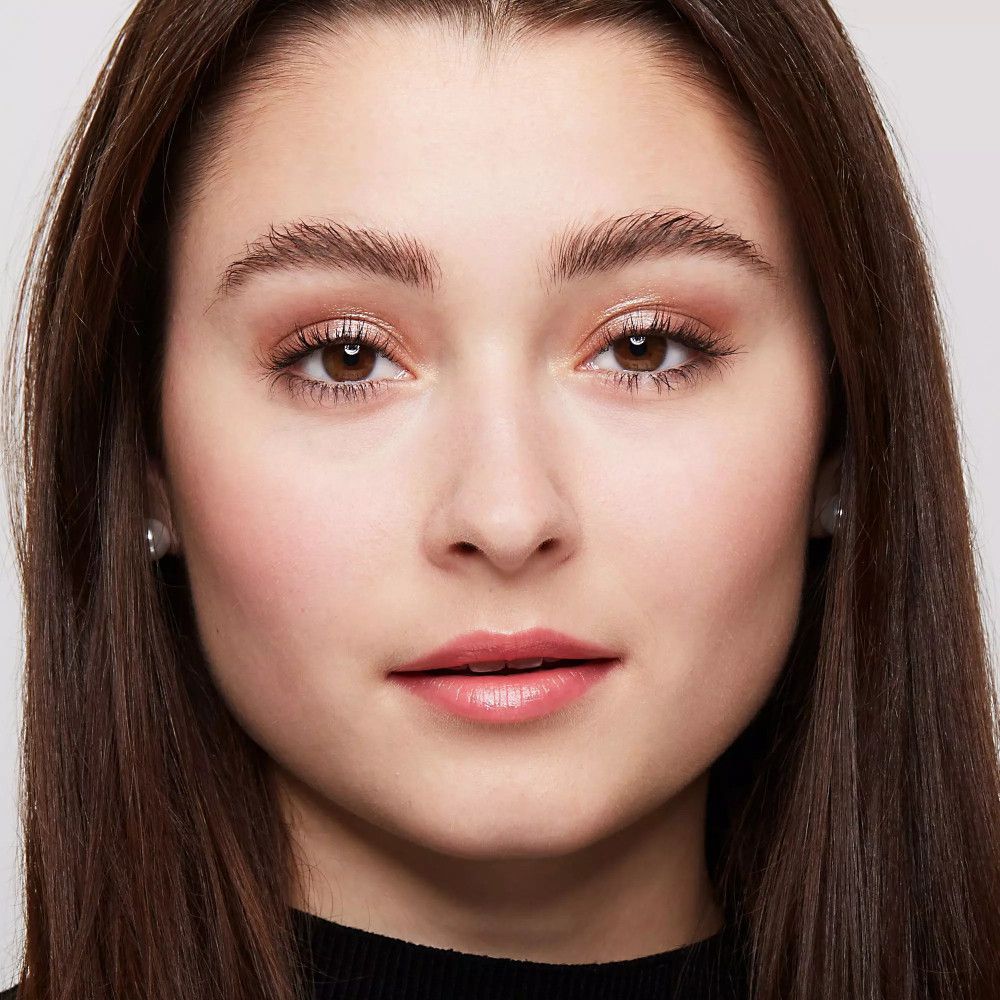 Gros plan sur le visage d'une femme avec des sourcils et des lèvres maquillés. Elle regarde la caméra.