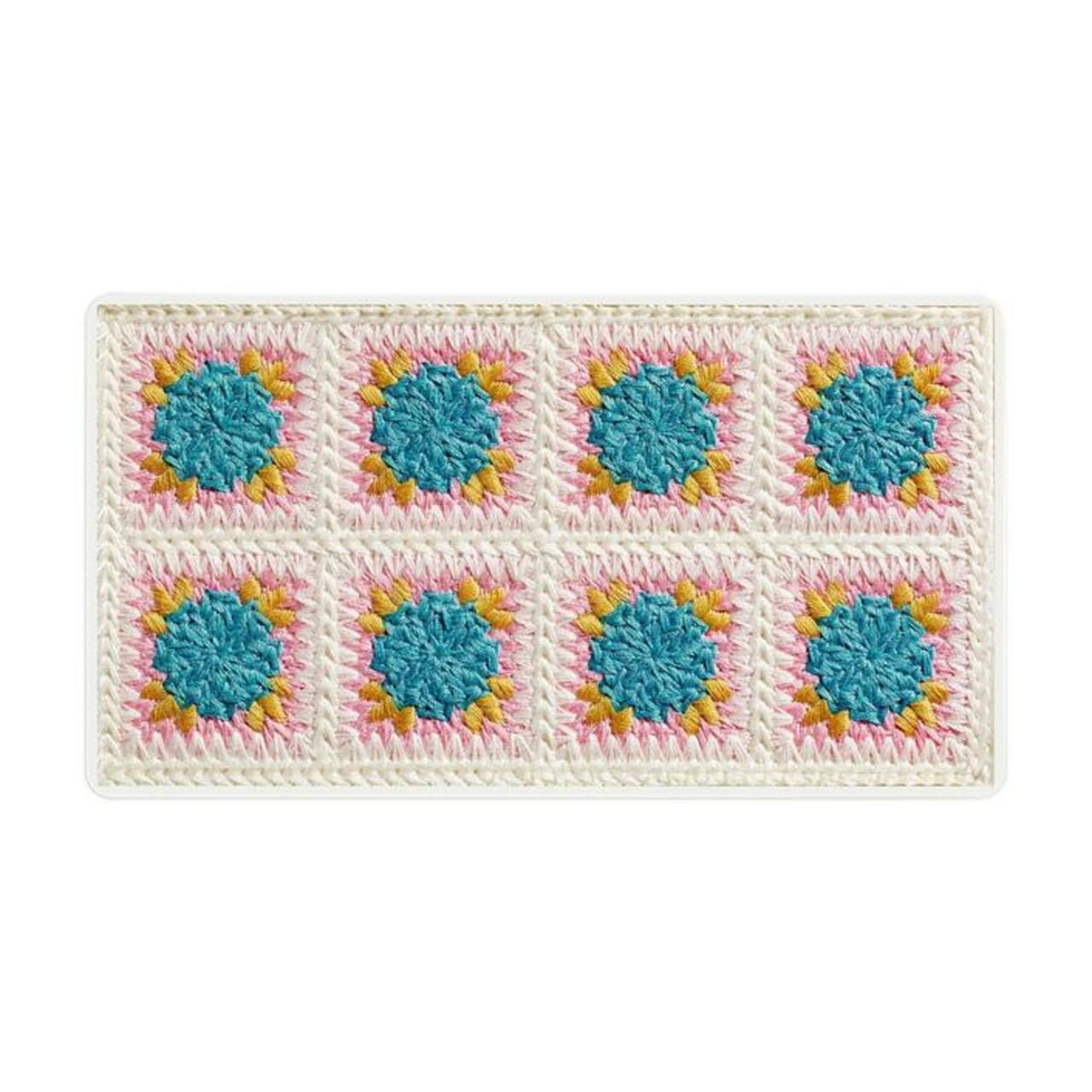 Rectangle crocheté avec huit motifs carrés. Motifs floraux turquoise, roses et jaunes sur fond blanc.