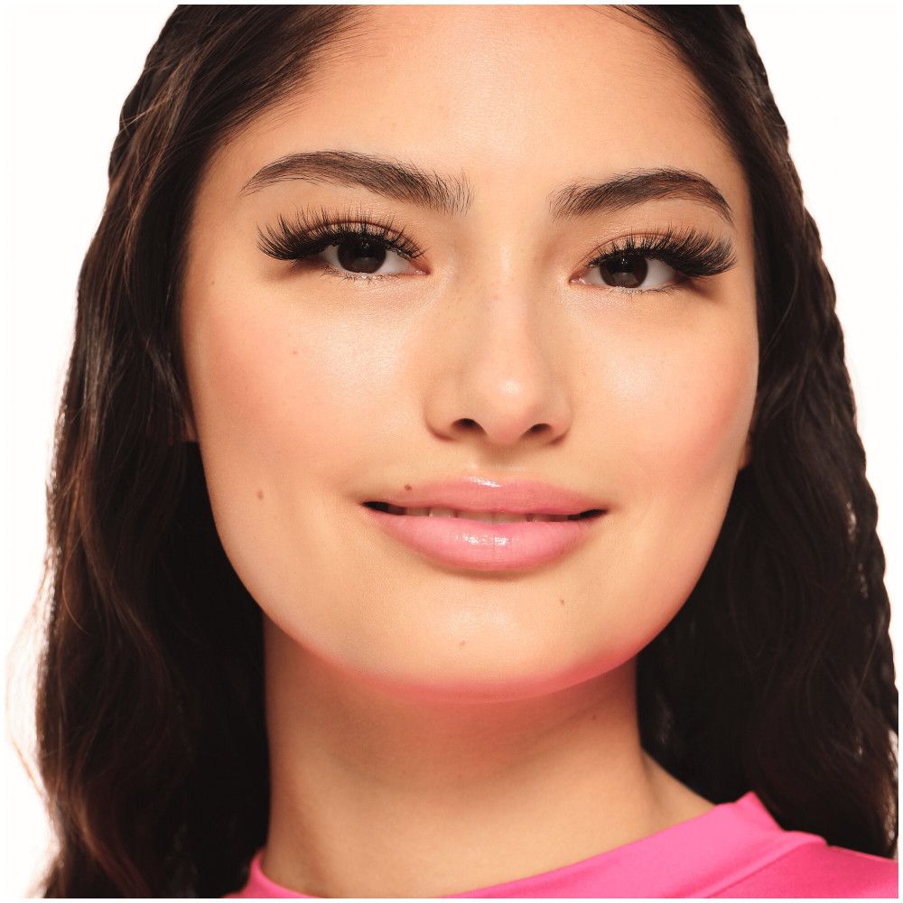 Portrait d'une femme avec de longs cils noirs. Elle porte un haut rose.