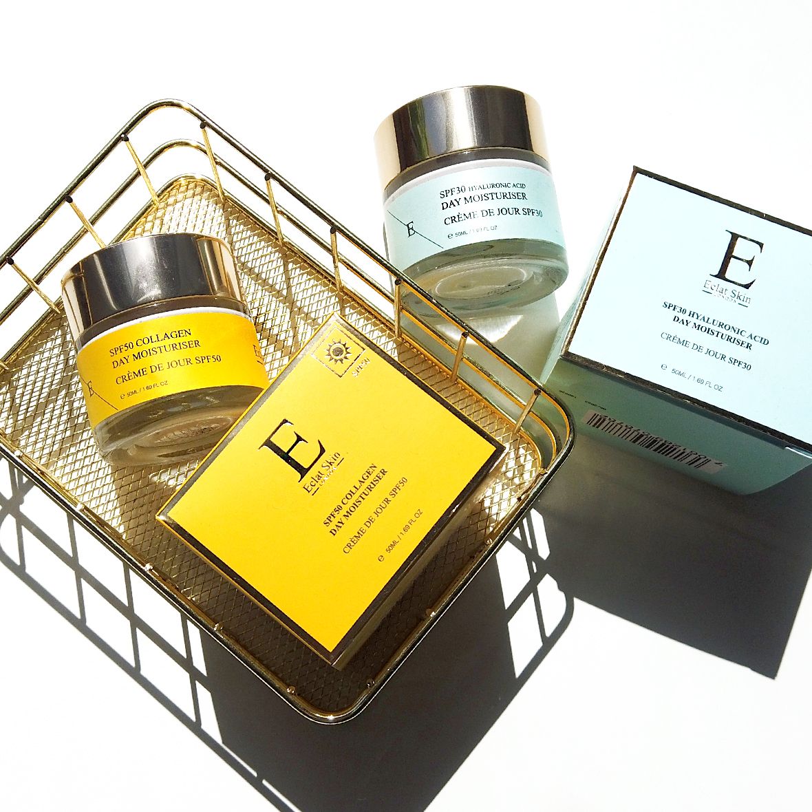 Twee crèmes en twee dozen in een gouden mand. Crèmes met gouden deksels en blauwe en gele etiketten. Dozen: "Erth Skin".