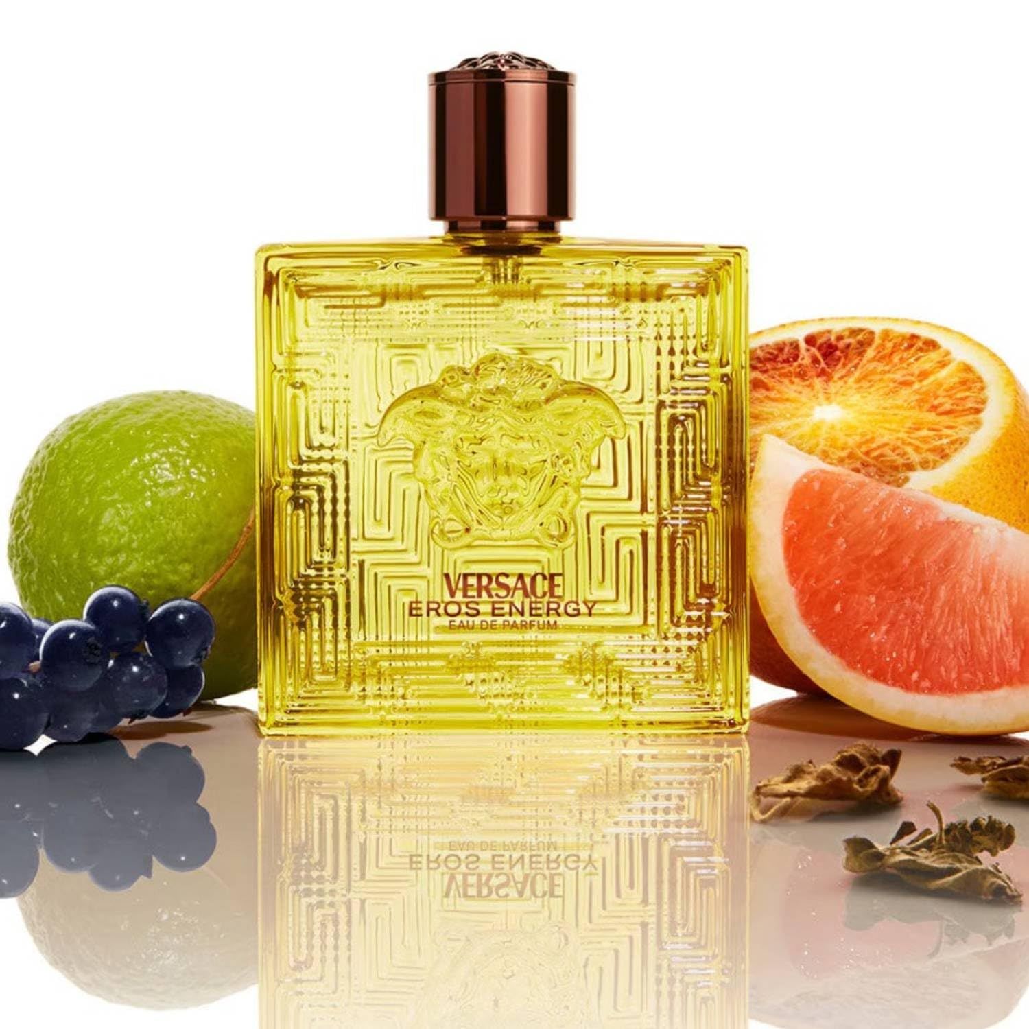 Flacon Versace Eros Energy EdP avec fruits. Flacon jaune, carré, logo Méduse. Fruits : pamplemousse, citron vert, raisins.