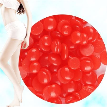Gros plan sur des perles de cire rouges à côté de la jambe d'une femme.
