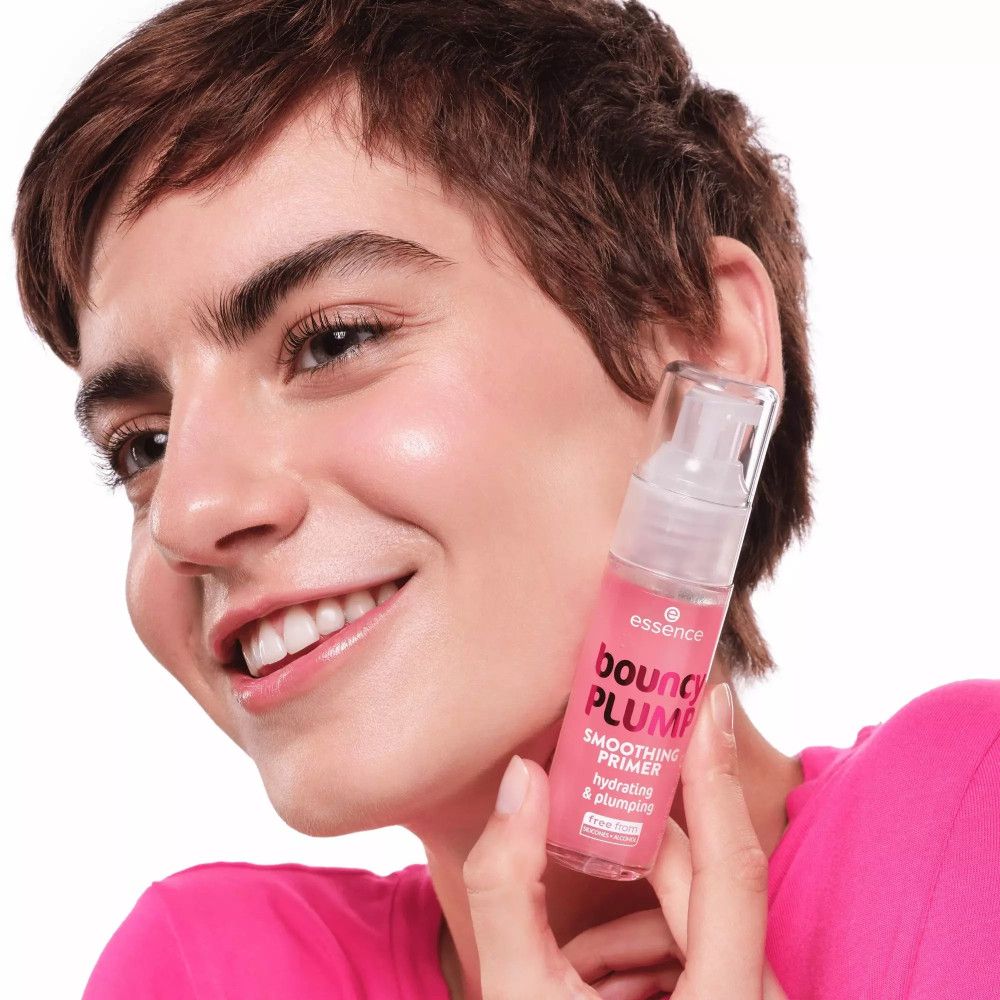 Une femme tient un flacon de primer pour le visage. Inscription : Bouncy Plump, Smoothing Primer, hydrating & plumping.