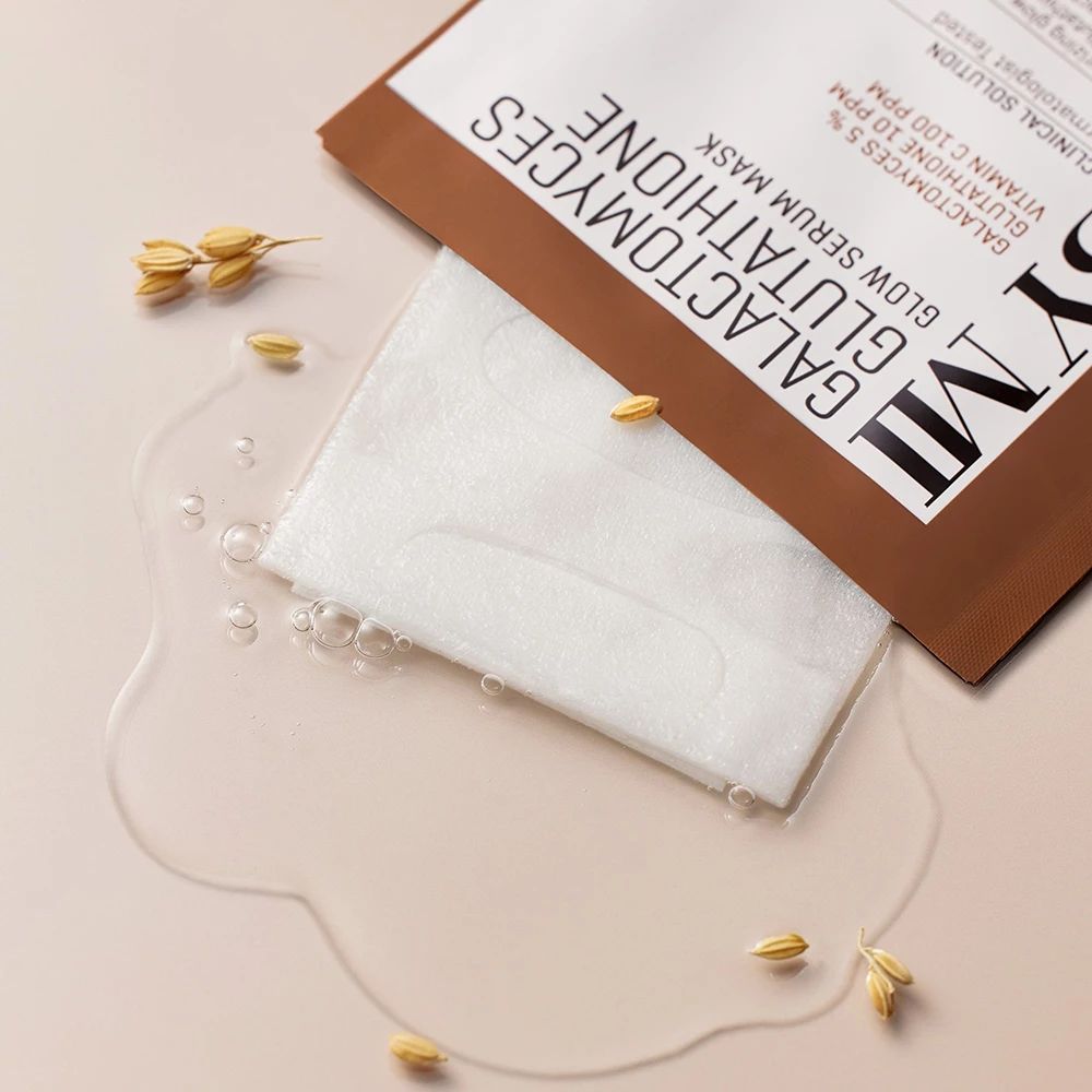 Open verpakking met serummasker. Daarnaast water en graankorrels. Opschrift: SOME BY MI, Galactomyces Glutathione Glow Serum Mask.