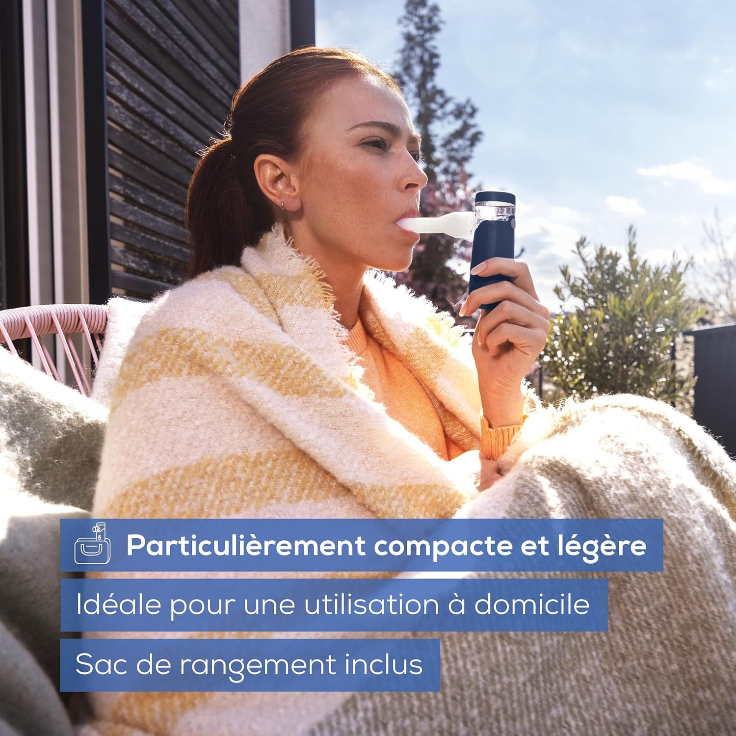 Une femme utilise un inhalateur portable avec un corps bleu et un embout blanc.