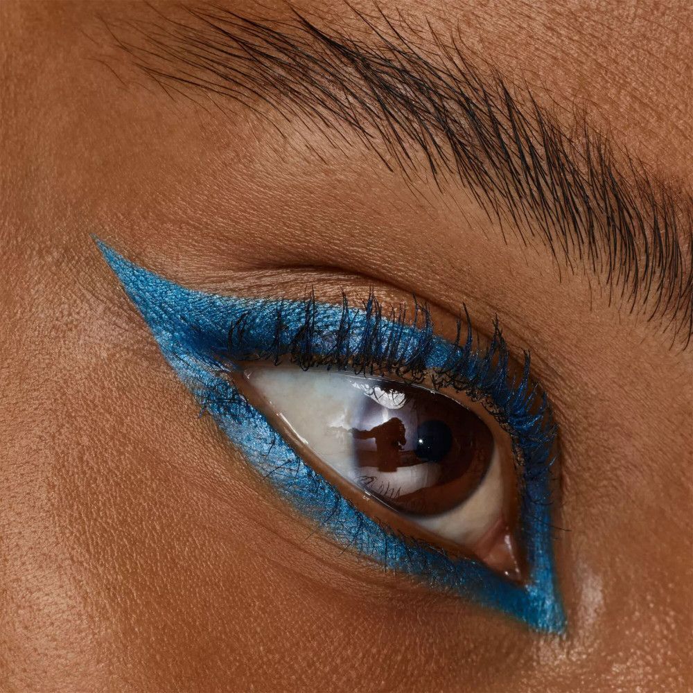 Œil avec crayon khôl bleu. Maquillage des yeux bleu. Yeux marrons, peau foncée.