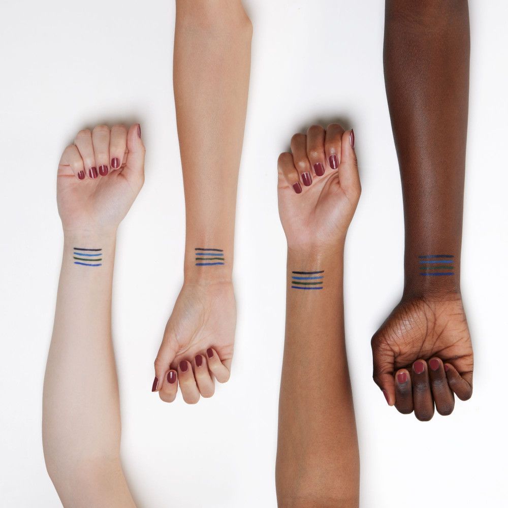 Quatre bras de teintes de peau différentes. Traits de kajal bleu appliqués sur les poignets.