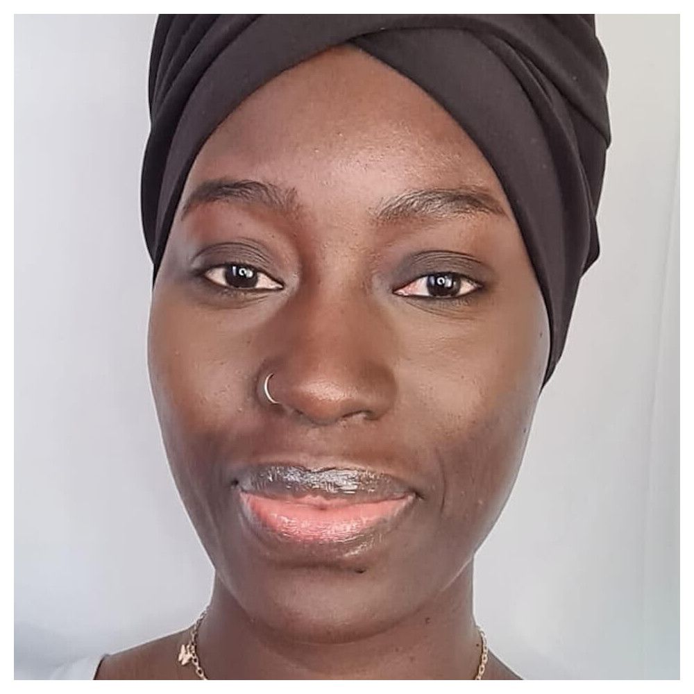 Portrait d'une femme à la peau foncée. Elle porte un turban noir. Visage maquillé.