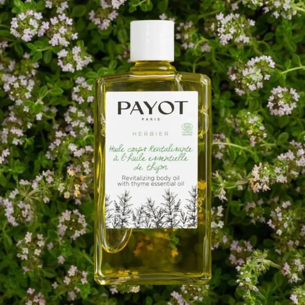 PAYOT Huile corps revitalisante à l'huile essentielle de thym dans une bouteille transparente, entourée de plantes.