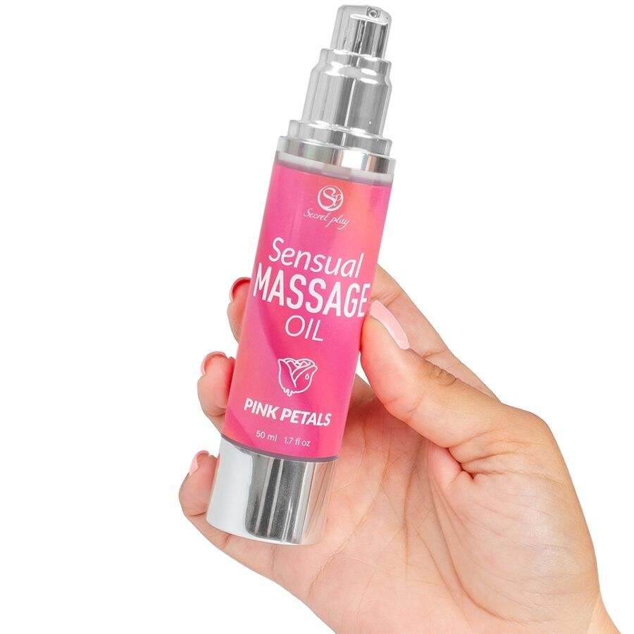Roze fles met zilveren verstuiver. Opschrift: Sensual Massage Oil Pink Petals. Vastgehouden door een hand.
