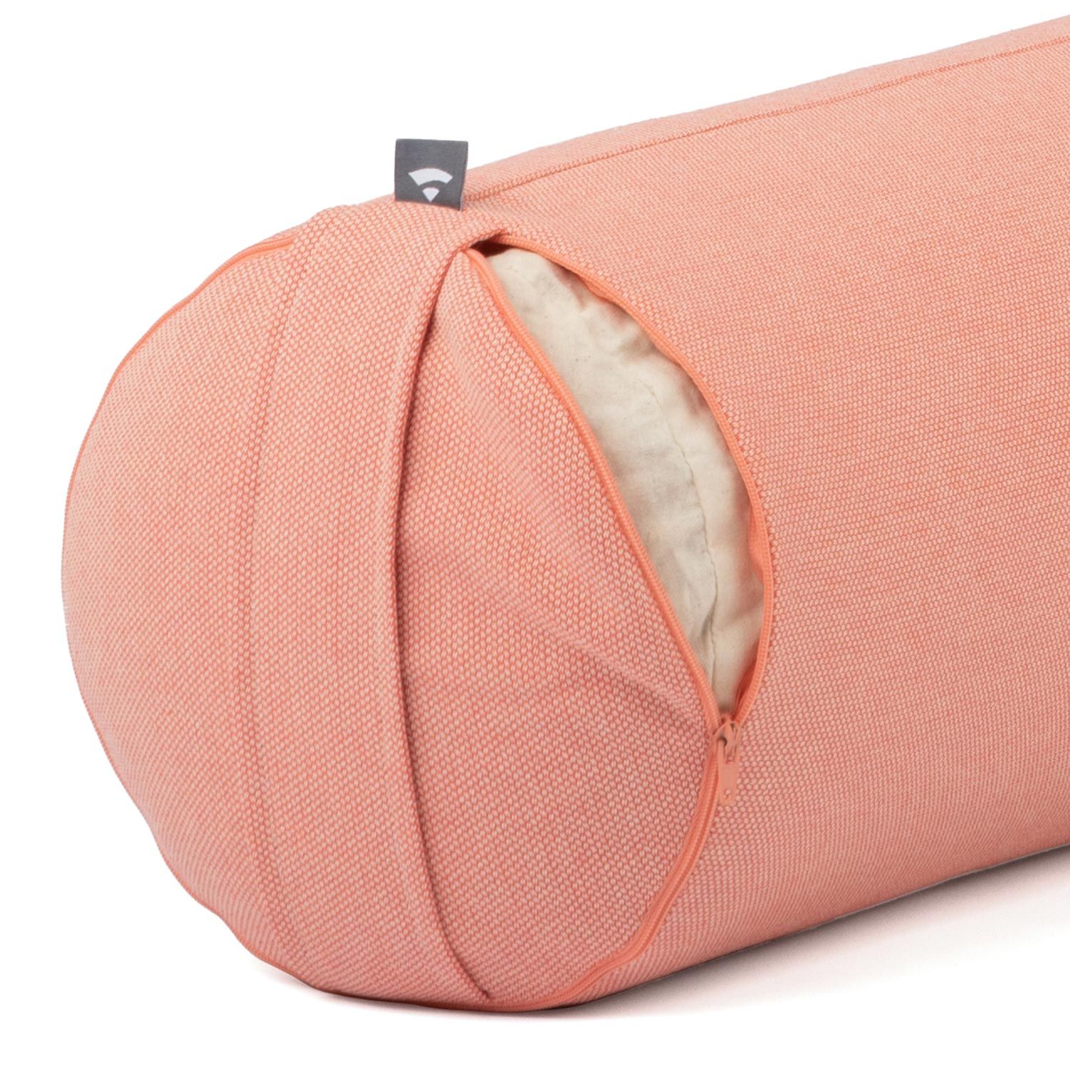 Close-up van een yoga bolster. Zalmroze stoffen hoes met rits. Klein label. Open uiteinde.