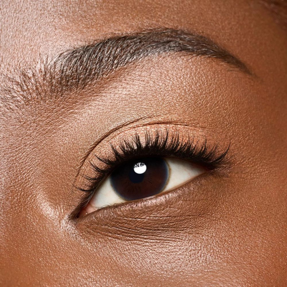 Gros plan sur un œil avec mascara et sourcils. La peau est bronzée.