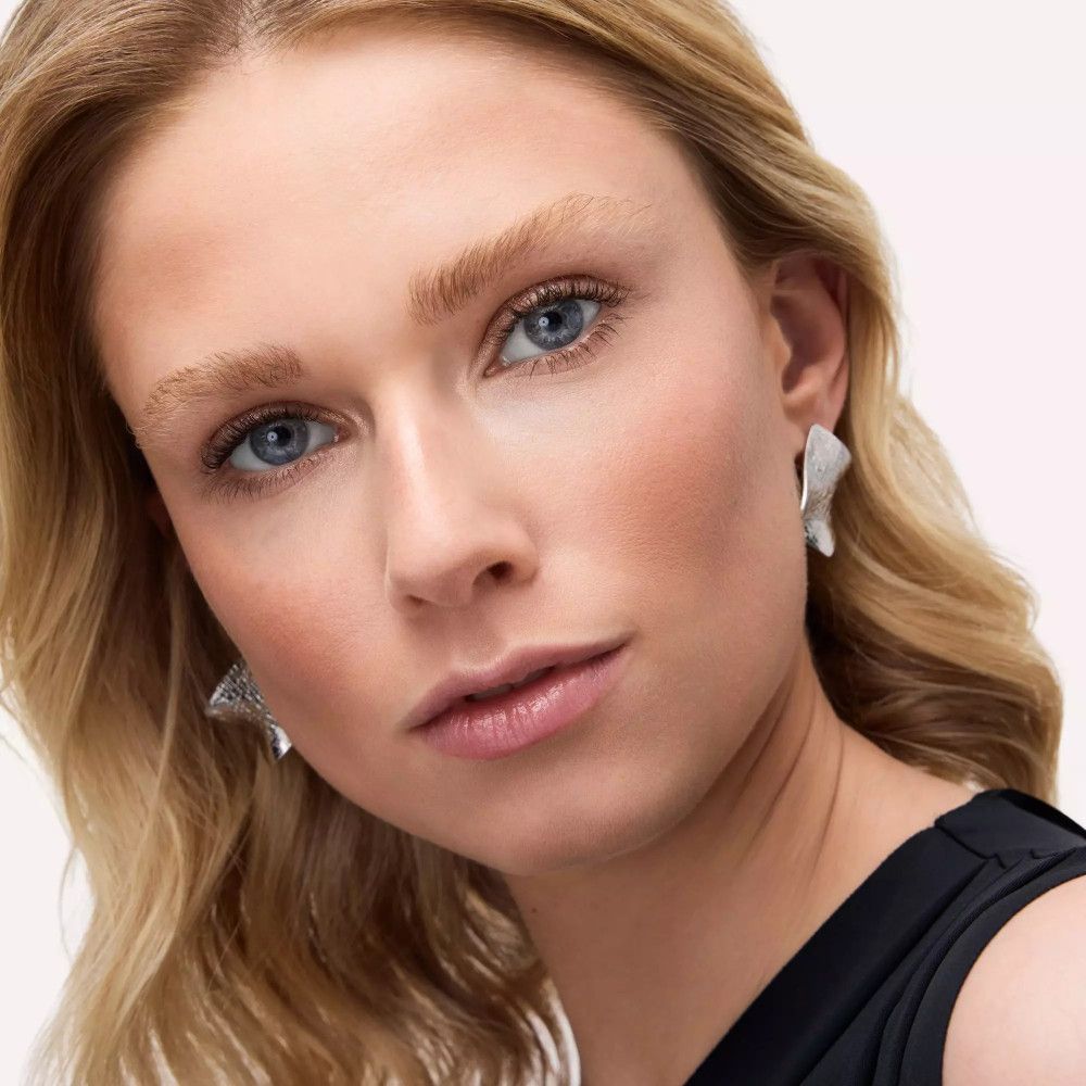 Portrait d'une femme aux cheveux blonds et aux boucles d'oreilles argentées.