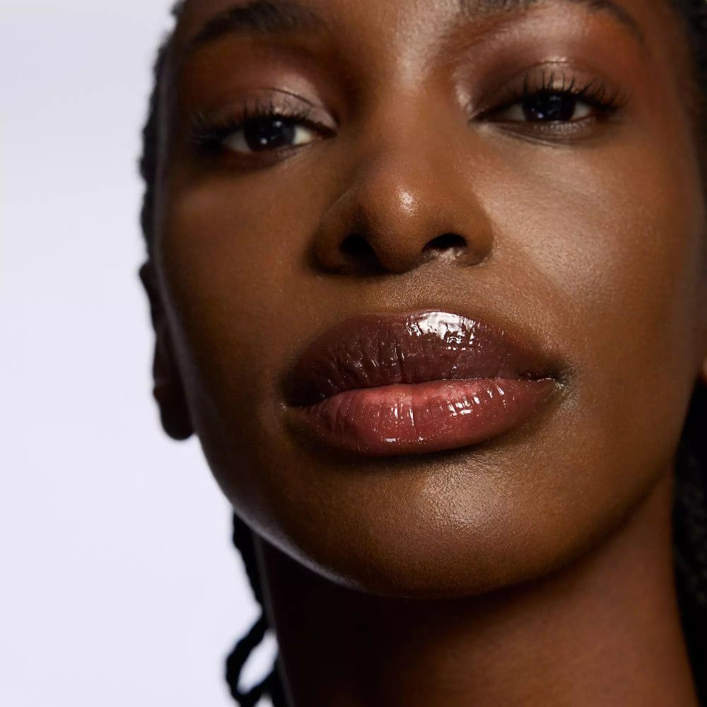 Close-up van lippen. Glanzende Lip Booster. Donkere huid. Witte achtergrond.