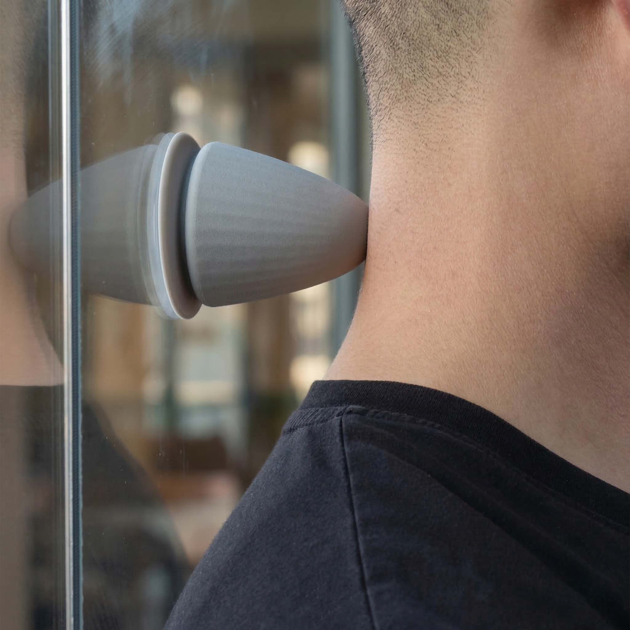 Grijs, kegelvormig product wordt op de nek van een persoon gebruikt. Reflectie op glas.