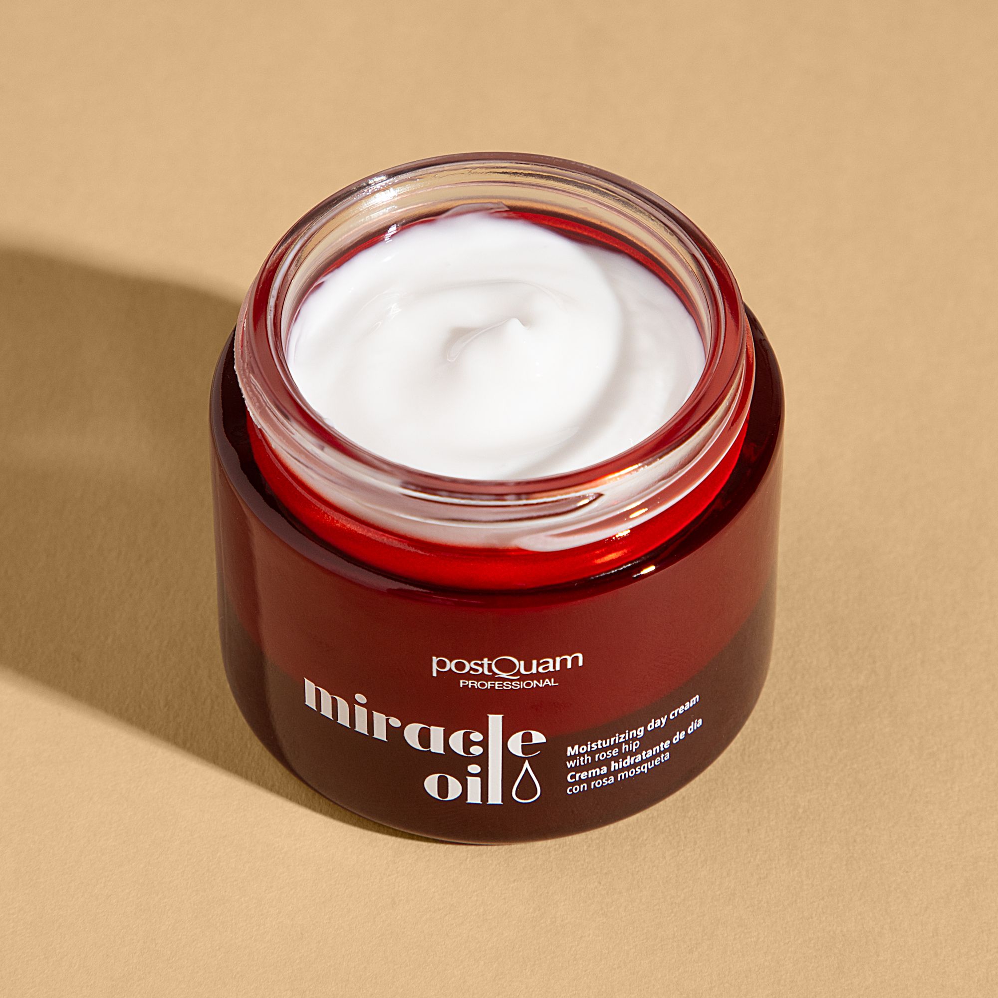 Open bruine crèmepot met witte crème. Opschrift: Postquam Professional, Miracle Oil. Tekst: Moisturizing day cream with rose hip.