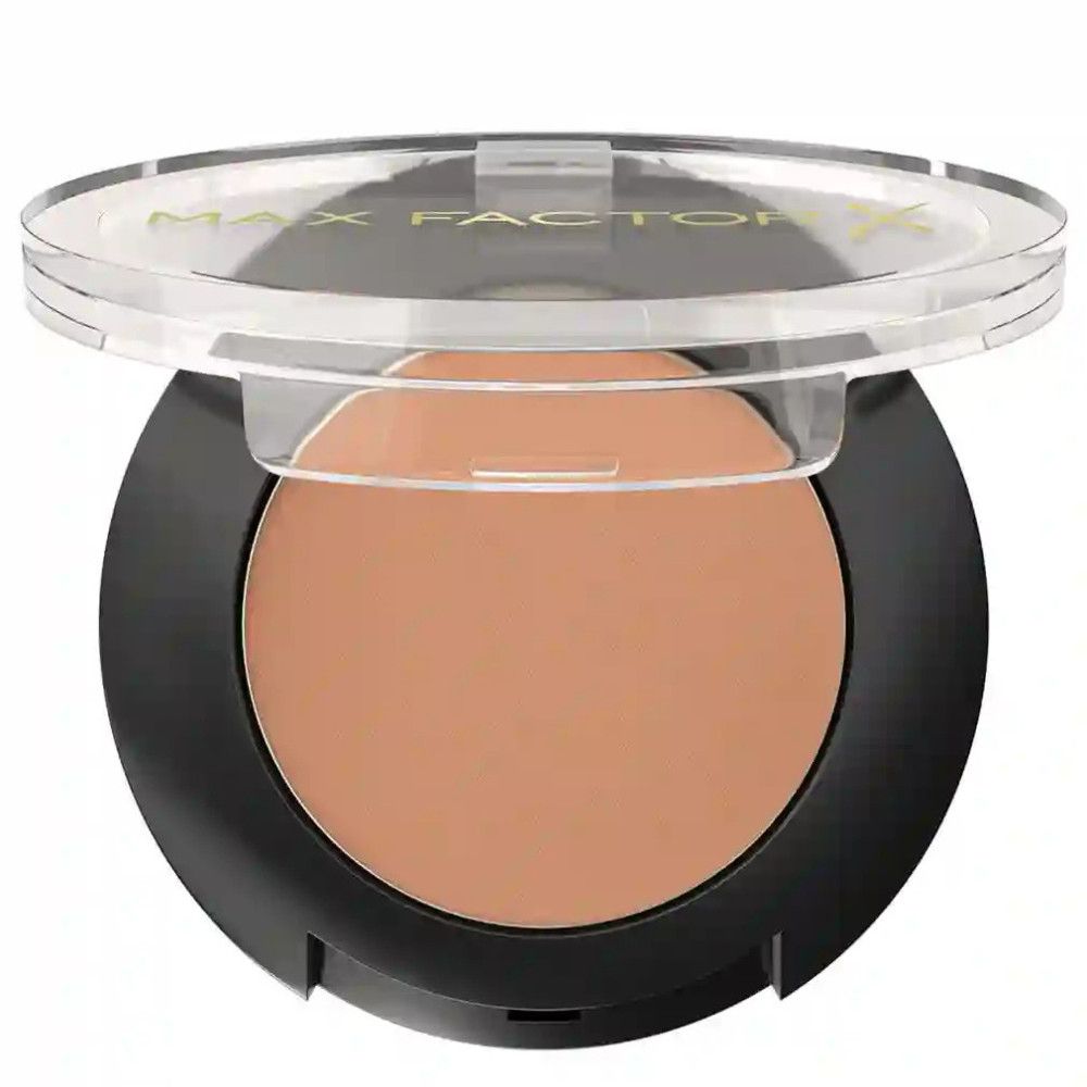 Ronde, zwarte oogschaduwverpakking met open transparante deksel. De oogschaduw is zichtbaar. De naam "MAX FACTOR" staat op de deksel.