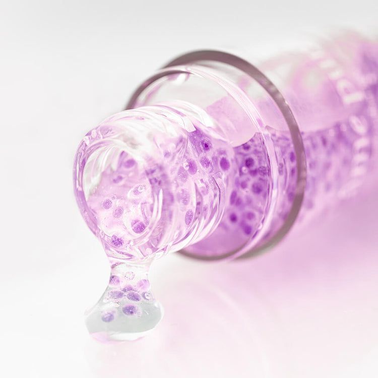 Close-up van een flacon Youth Concentrate Serum, serum druipt eruit.