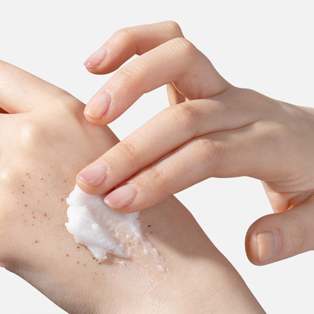 Main appliquant le TIRTIR Hydro Boost Enzyme Cleansing Balm sur l'autre main tachetée.
