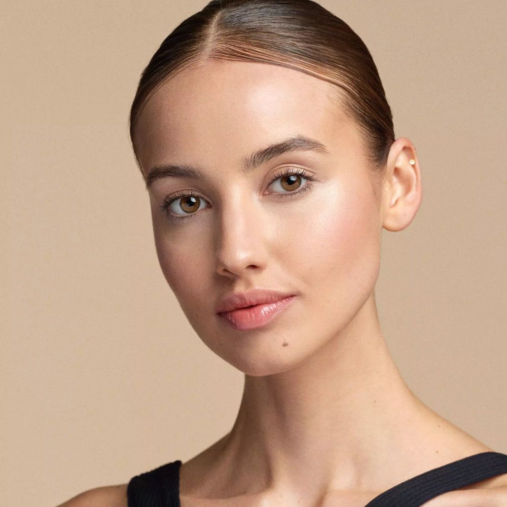 Portret van een vrouw met een gladde huid en subtiele make-up. Gouden glans op de wangen.