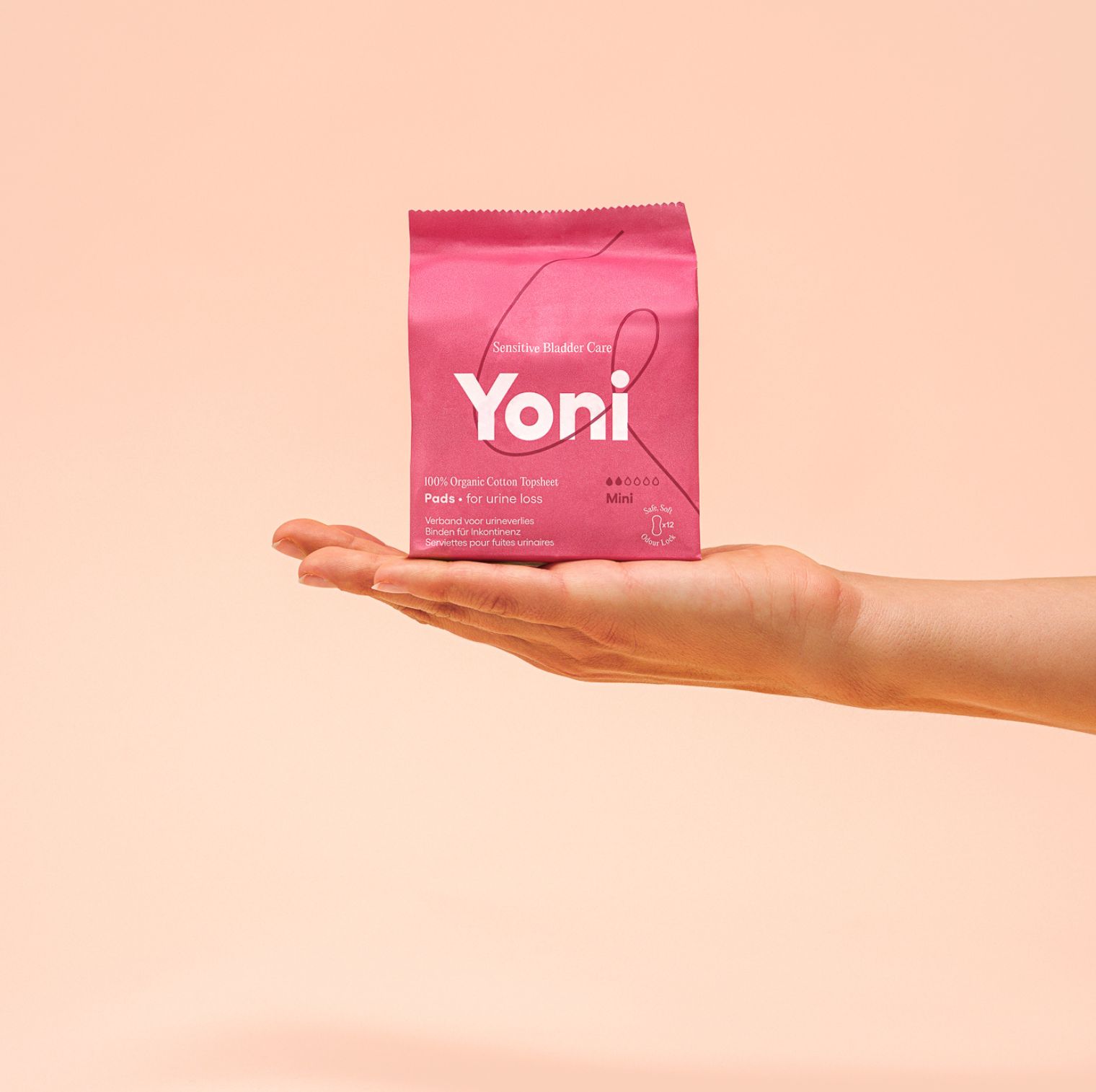 Roze verpakking met productnaam Yoni. Opschrift: Pads voor urineverlies. Vastgehouden door een hand.