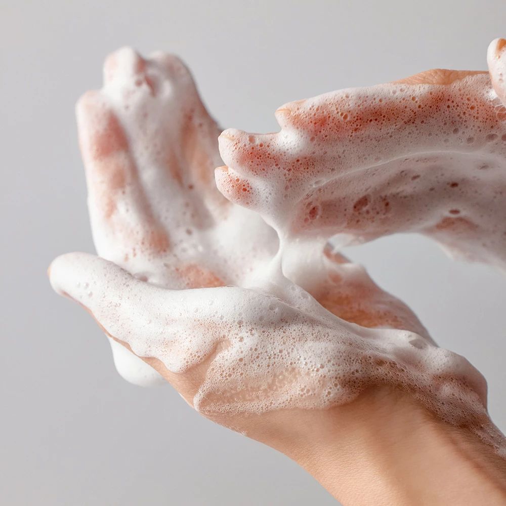 Handen bedekt met wit schuim. Het schuim is overvloedig en bedekt de handen.