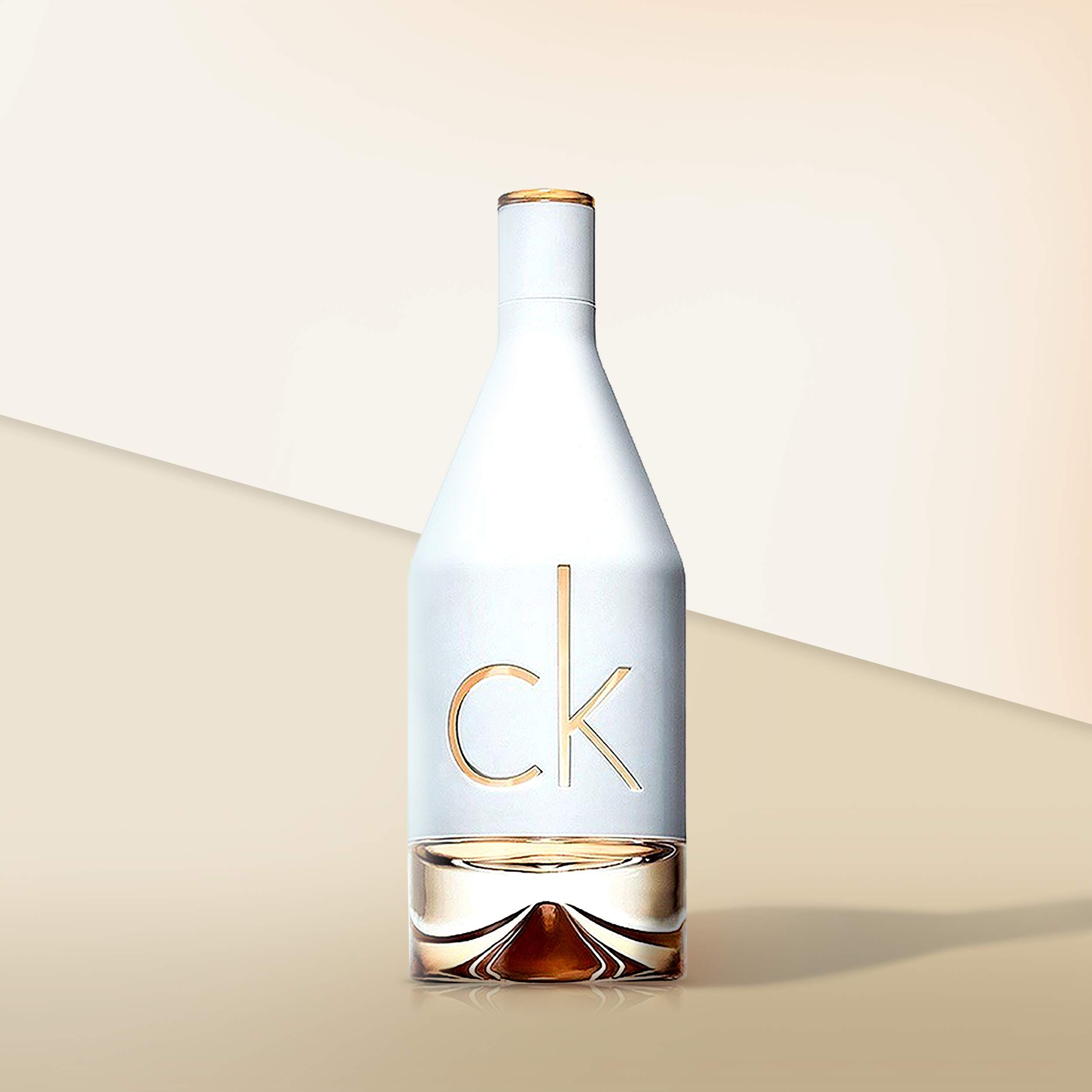 Flacon de parfum Calvin Klein In2u, verre blanc, lettrage doré. Base remplie de liquide. Logo CK.