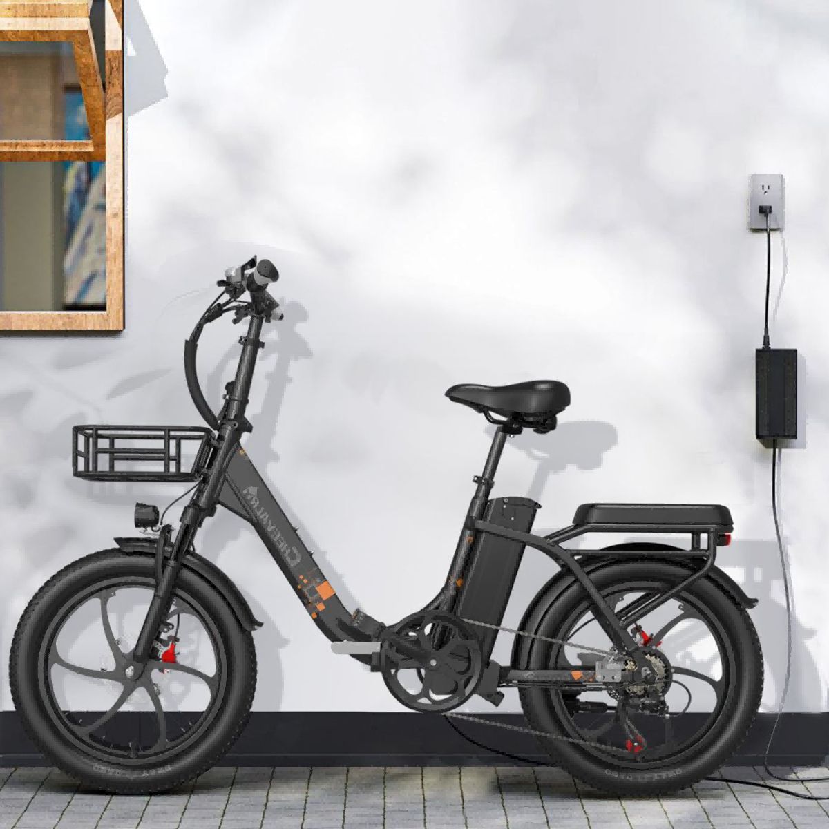 Vélo électrique noir avec panier, contre un mur avec prise et chargeur. Selle et guidon visibles.