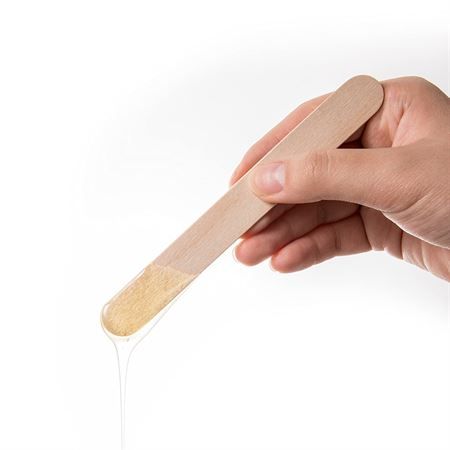 Hand die een houten spatel met wax vasthoudt.