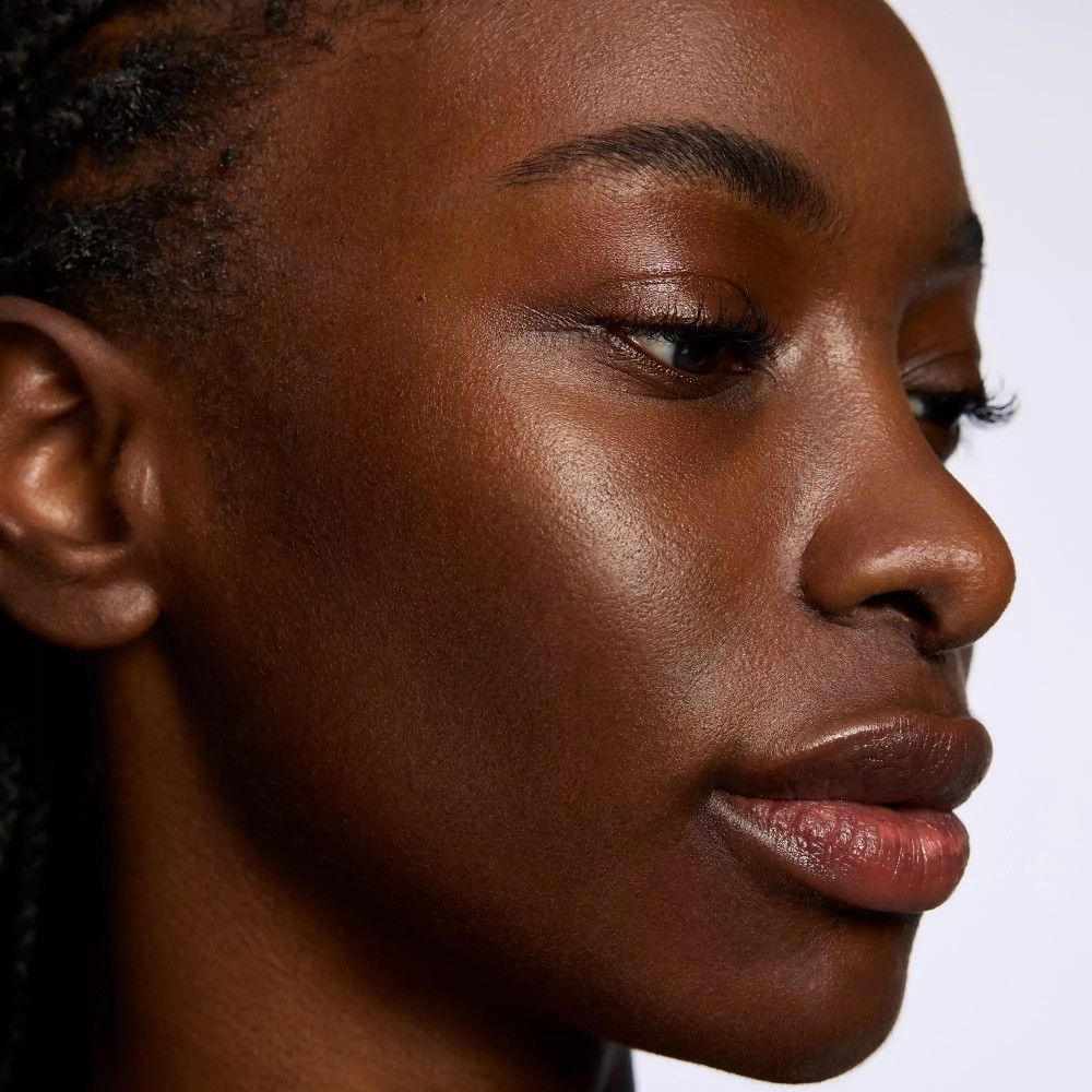 Close-up van een gezicht. Donkere huid, gedefinieerde wenkbrauwen, glanzende huid.