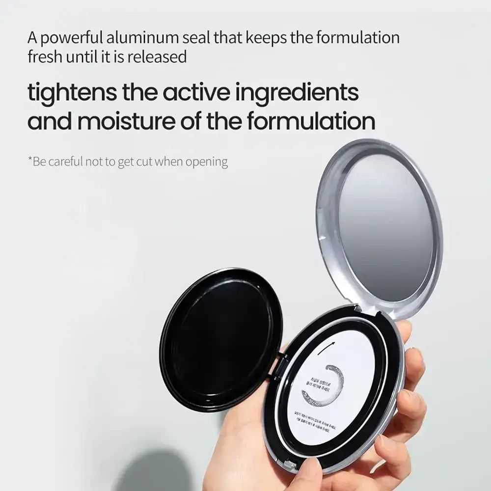 Produit cosmétique argenté ouvert. Miroir et éponge visibles. Avertissement : attention à ne pas se couper lors de l'ouverture.