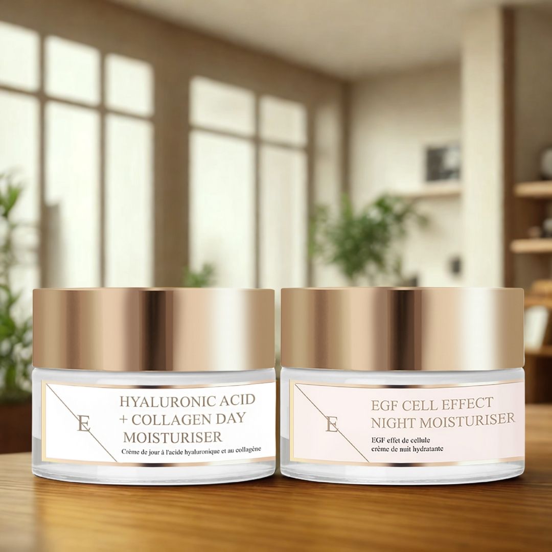 Twee crèmepotten met gouden deksels en etiketten. Opschrift: Hyaluronzuur + collageen dagcrème en EGF Cell Effect nachtcrème. Op tafel.