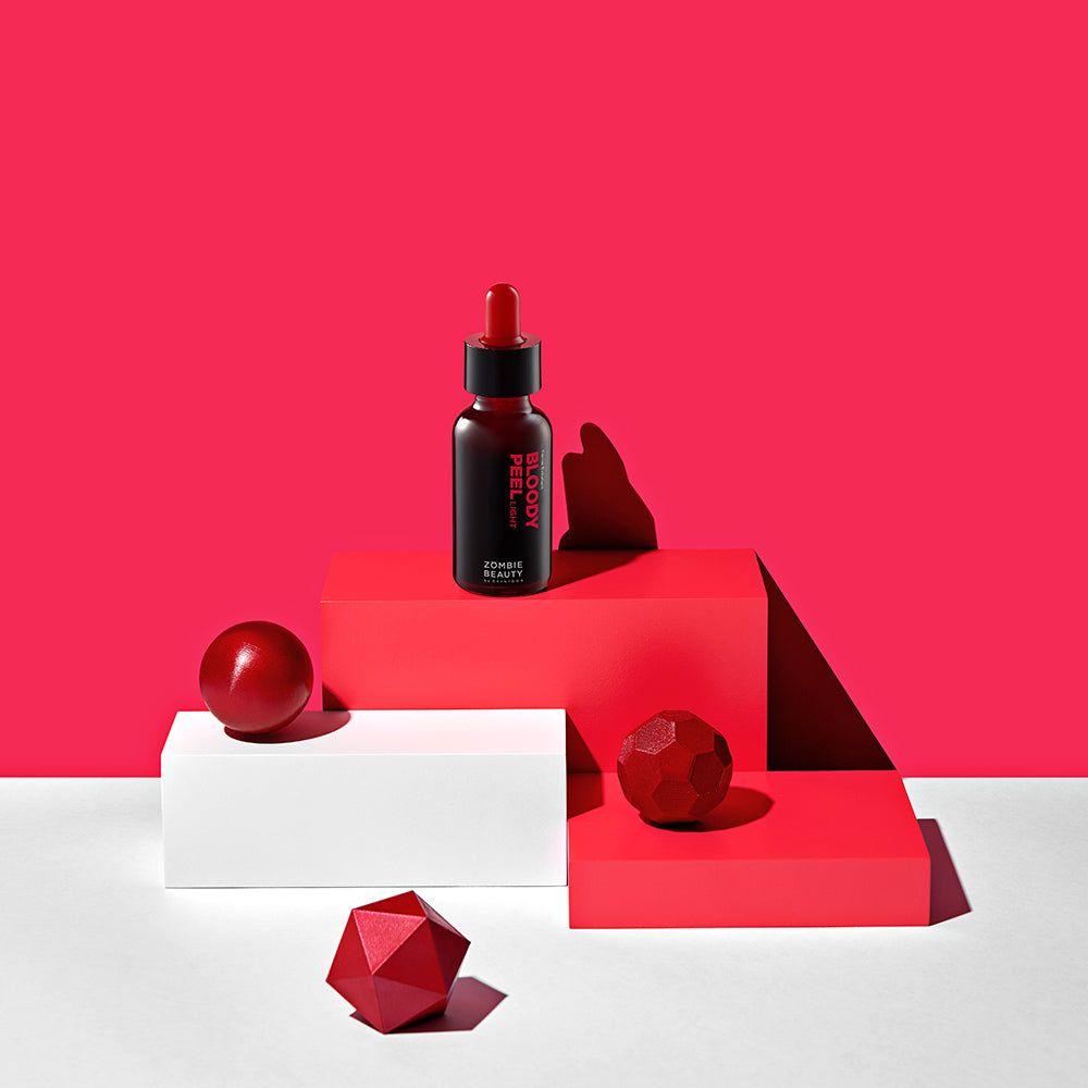 Product op sokkels. Fles met rode vloeistof, bollen en geometrische vormen. Rode achtergrond.