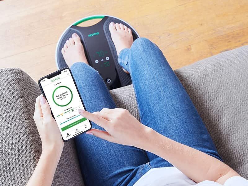 Gros plan : Pieds sur le REVITIVE Medic Coach, utilisation de l'application smartphone.