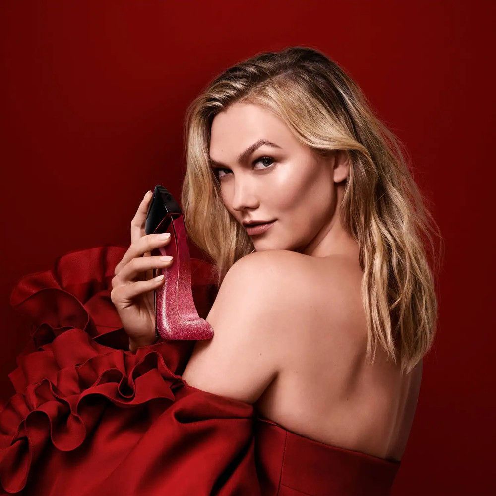 Femme tenant le flacon de parfum Carolina Herrera Very Good Girl Glam en forme de chaussure.