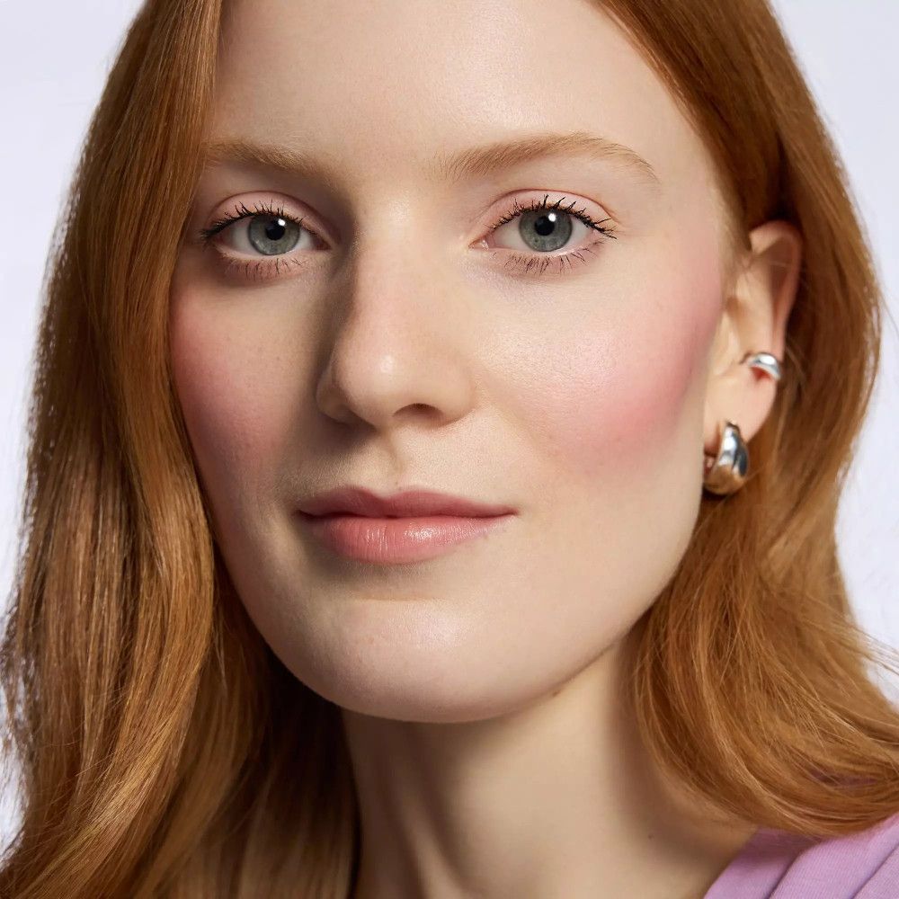 Portrait d'une femme avec du baume à lèvres. Cheveux roux, maquillage discret.